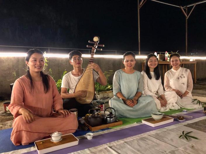five young chinese adults sitting on a rooftop at night during a celebration