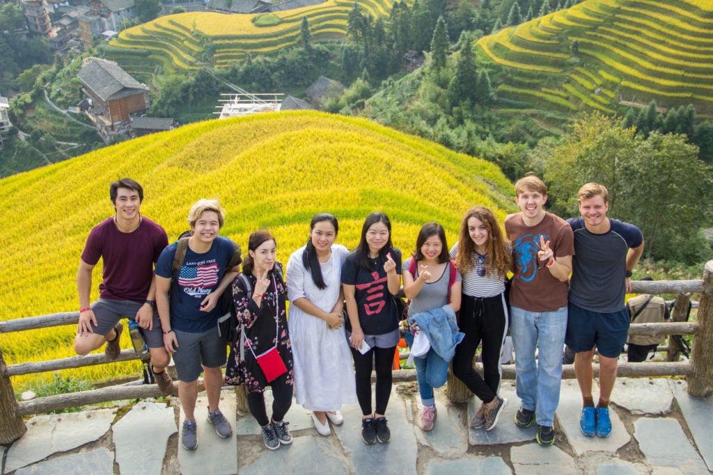 Un grupo de estudiantes de la CLI posa con terrazas de arroz amarillo de fondo