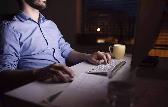 a man sits in front of a computer late at night