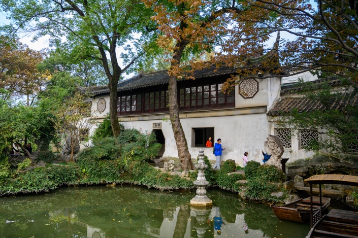visitors and a Suzhou travel guide walking beside a pond in the Lingering Garden, Suzhou