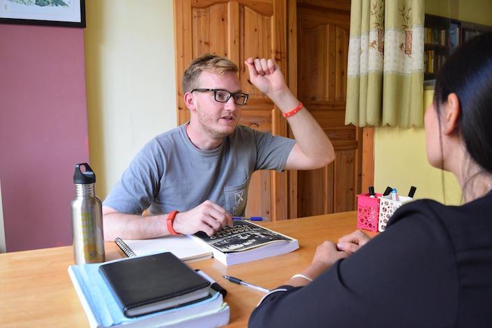 a blond CLI student talking with his Chinese teacher