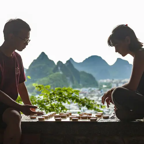 Two people sitting outdoors in Guilin with a mountain view behind them