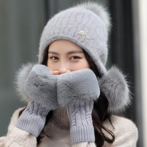 una niña china sonriendo mientras usa un sombrero gris y guantes