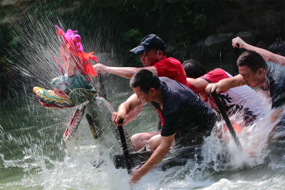 photo d'hommes ramant un bateau-dragon pendant le festival des bateaux-dragons, une fête chinoise populaire