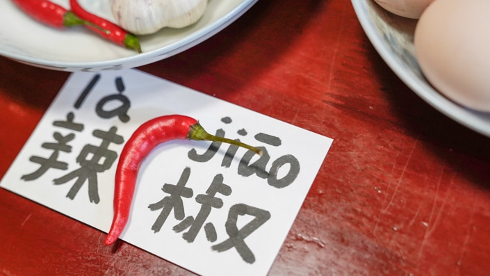 un pimiento rojo sentado encima de un papel con la palabra china para ají escrito en él