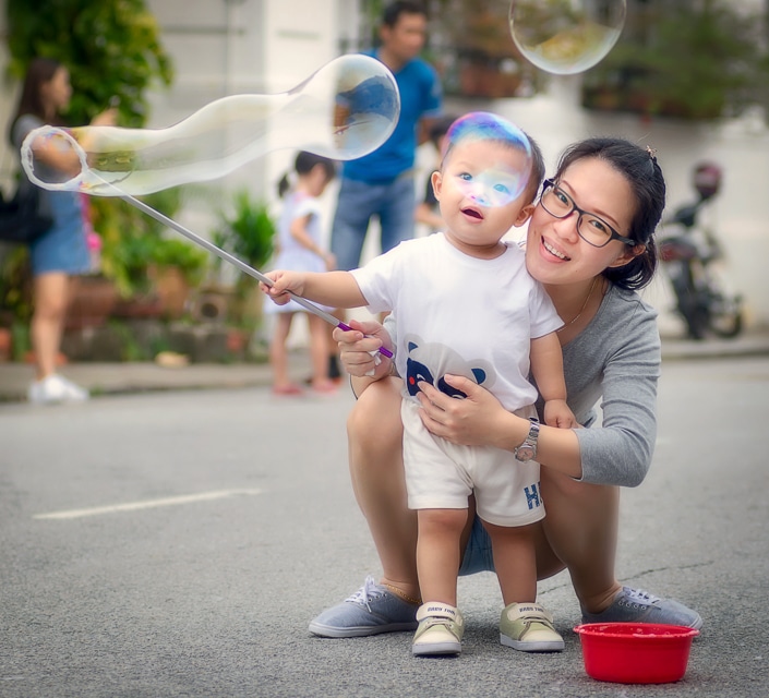 una madre china ayudando a un niño a soplar burbujas