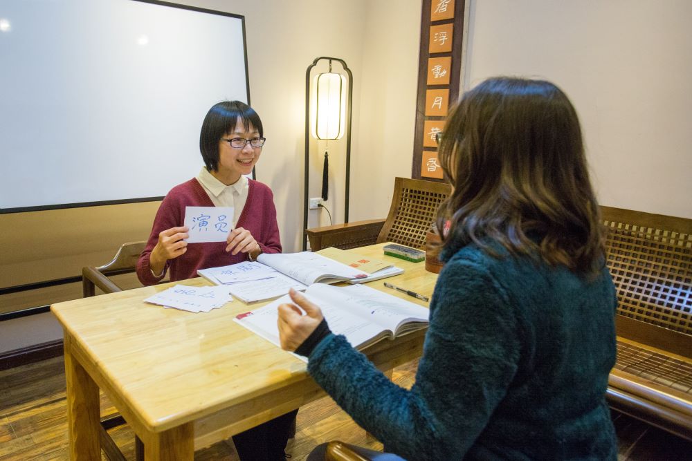 a teacher teaching a student using Chinese flashcards