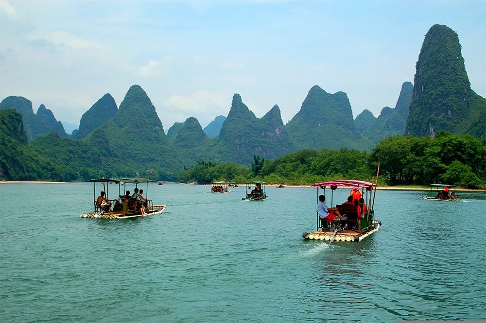 Yangshuo travel guides and visitors ride bamboo rafts on a river