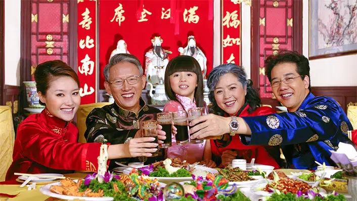 une famille chinoise trinquant autour d'un repas de fête chinois