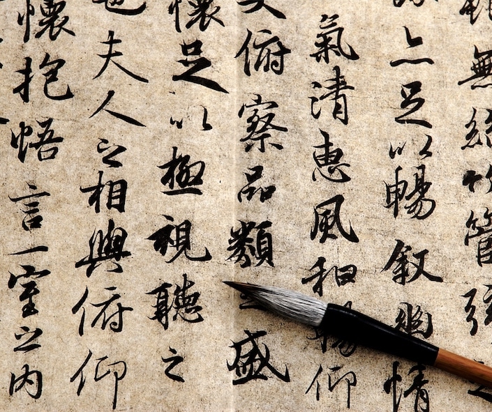 picture of a Chinese calligraphy brush sitting on a paper with Chinese characters written in ink