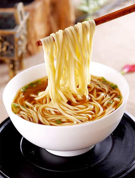 a photo of a bowl of noodles, a traditional birthday food in China