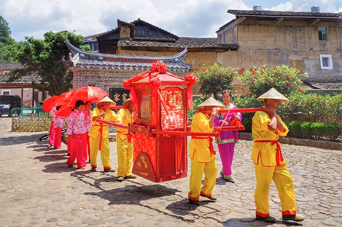 Guests celebrating at a Chinese wedding banquet with red decorations