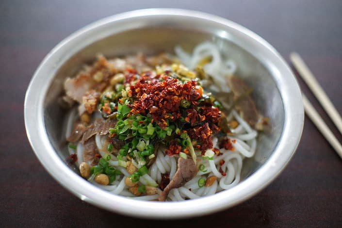 a bowl of Guilin rice noodles topped with ground chili peppers