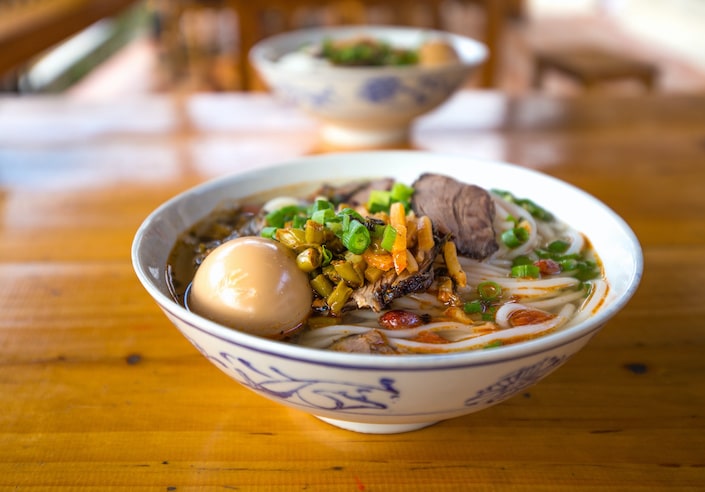 a white and blue bowl of Guilin rice noodles seen from the side