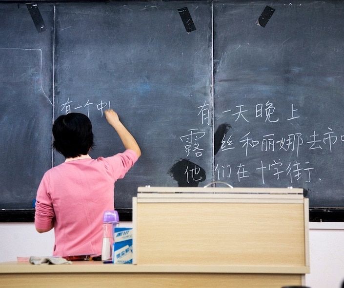a teacher writing HSK vocabulary words on a blackboard