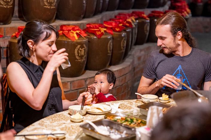 두 명의 CLI 학생과 저녁을 먹고 있는 작은 중국 아이