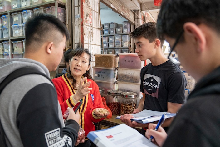 a Chinese woman talks with students about Chinese medicine