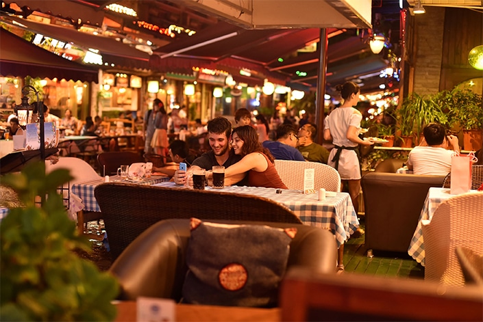 un hombre y una mujer se sientan en una mesa en un restaurante al aire libre