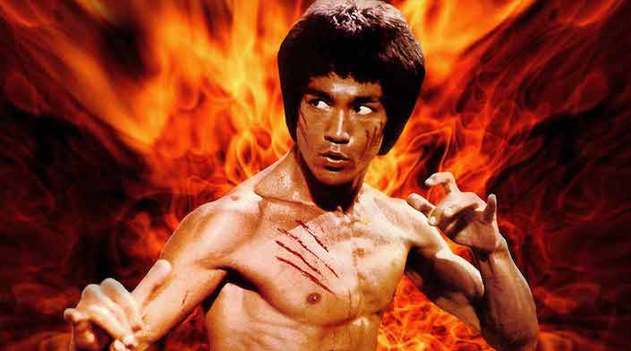 a shirtless Bruce Lee in a Chinese martial arts pose with flames in the background