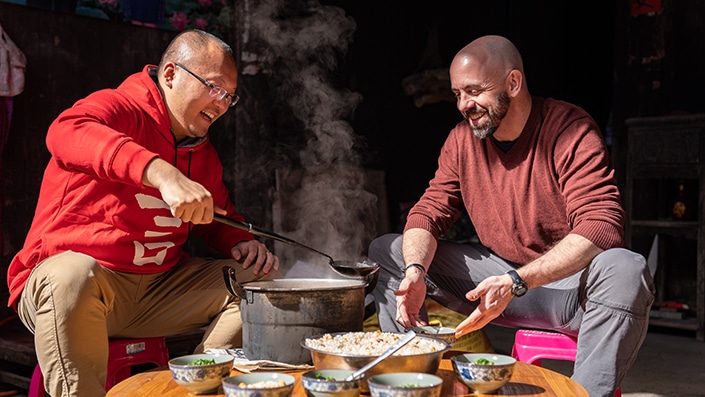 a CLI staff member serving as a Yangshuo travel guide gives a student a ladle of oil tea