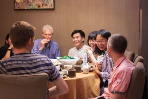Friends laugh together around a table set with teacups