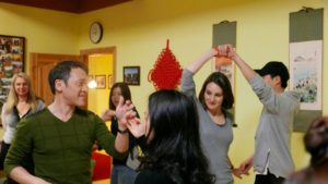 People dance with partners under a red Chinese knot in a yellow room