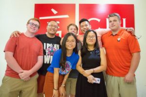 A group in bright T-shirts poses in front of the red CLI sign