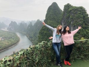 Two women stretch their arms wide above a bend in the Li River