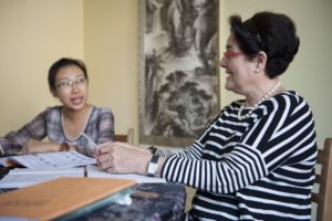 A student and teacher talk across a table with open workbooks