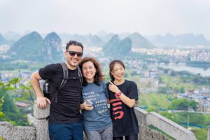 Three friends pose at a lookout above Guilin's city and karst hills