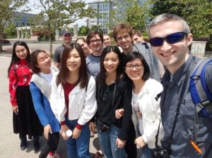A group of friends takes a selfie outdoors on a sunny day