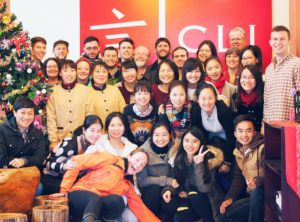 A large group poses by the CLI sign and a Christmas tree