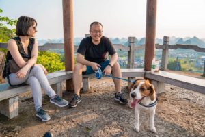 Two people sit in a hilltop pavilion with a beagle beside them