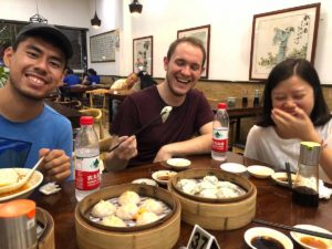 Three friends laugh over steamed buns and dim sum at a restaurant