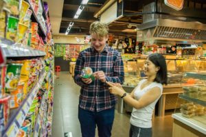 A man and a woman look at a snack package in a supermarket aisle