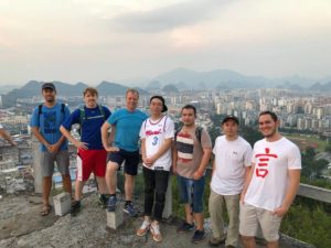 A group of men stands on a hilltop above Guilin's skyline