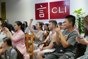 A crowd watches and films a performance in front of the CLI sign