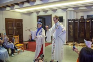 Two people in Chinese opera costumes perform in a meeting room