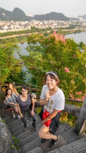 Friends sit on stone steps among flowers above the city
