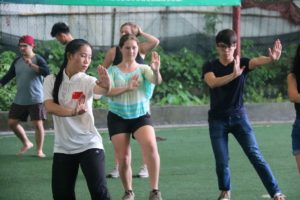 A group practices martial arts moves together on a turf field