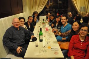 Friends gather at a long dinner table in a restaurant