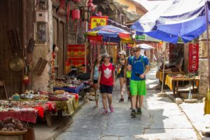 Two visitors walk through an old town street lined with stalls