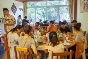 Diners share a meal at round tables in front of large green-view windows