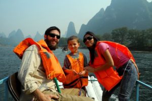 Three people in life jackets ride a boat on the Li River