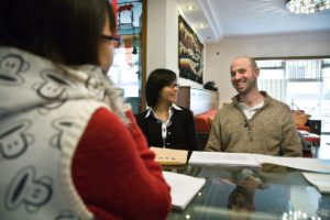 A student and teachers talk across a glass table during class