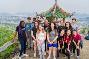 A group poses by a pavilion on a hill above Guilin