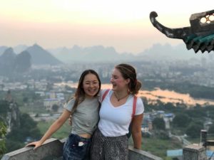Two women smile at a pavilion lookout over Guilin at sunset