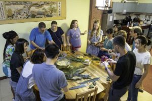 A group prepares food together around a big table during a cooking class