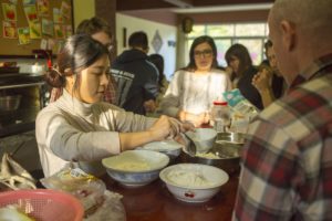 People mix dough in bowls on a kitchen counter during a cooking class