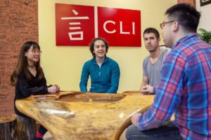 A small sits around a wooden table under the CLI sign